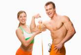 Woman measuring man's bicep, smiling, portrait
